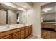 Bathroom with double sinks in a wood vanity, large mirror, and view into bedroom at 2055 Mulsanne Dr, Zionsville, IN 46077