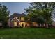 Traditional brick home with lush green lawn, mature trees and a well-lit exterior at 2055 Mulsanne Dr, Zionsville, IN 46077