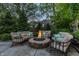 Outdoor fire pit with comfortable seating area and a lush, green backyard with mature trees and landscaping at 2055 Mulsanne Dr, Zionsville, IN 46077