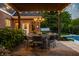 Outdoor patio area with a chandelier, dining table, and a view of a lush landscaped backyard and pool at 2055 Mulsanne Dr, Zionsville, IN 46077