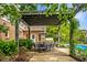 View of outdoor dining under pergola, brick home, and blue skies in the backyard at 2055 Mulsanne Dr, Zionsville, IN 46077
