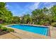 Backyard view of a rectangular pool surrounded by greenery, patio and lounge chairs at 2055 Mulsanne Dr, Zionsville, IN 46077