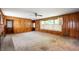 Spacious living room with wood paneling, large window, and classic carpeting, providing a comfortable gathering space at 301 N Kitley Ave, Indianapolis, IN 46219