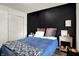 Bedroom featuring a dark accent wall and wood flooring, with a cozy bed and bedside table at 3214 Limber Pine Dr, Whiteland, IN 46184