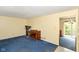 Bright living room featuring blue carpeting and a piano, leading to another room with a sliding glass door at 3325 Broadview Ct, Indianapolis, IN 46227