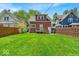 A lush green backyard with a charming house and wooden fence offers a serene outdoor space at 405 N Drexel Ave, Indianapolis, IN 46201