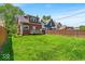 View of the spacious, green backyard featuring lush grass and a wooden fence on a sunny day at 405 N Drexel Ave, Indianapolis, IN 46201