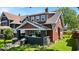 Charming home featuring a covered front porch with flowers, a dark gray foundation, and a brick chimney at 405 N Drexel Ave, Indianapolis, IN 46201