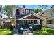 Charming two-story home featuring a covered front porch with flowers, a dark gray foundation, and a brick chimney at 405 N Drexel Ave, Indianapolis, IN 46201