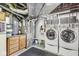 Clean laundry room with washer and dryer, storage cabinets, and utility sink at 5002 Broadway St, Indianapolis, IN 46205