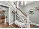 Bright entryway featuring hardwood floors, a staircase with white railings, and stylish decor at 5002 Broadway St, Indianapolis, IN 46205