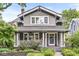 Charming two-story home with a covered front porch, lush landscaping, and inviting curb appeal at 5002 Broadway St, Indianapolis, IN 46205