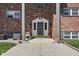 Close up of a brick condominium building featuring a front door with a small porch and American flags at 5038 Allisonville Rd # E, Indianapolis, IN 46205