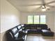 A clean living room with a large leather sofa, light-colored walls, and a view of the outdoors through a large window at 5200 N Leslie Dr, Muncie, IN 47304