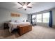 Spacious carpeted bedroom featuring a ceiling fan, dresser, chest, and a treadmill at 5522 Grassy Bank Dr, Indianapolis, IN 46237