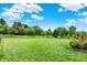 Spacious backyard with lush green lawn, mature trees, and a black chain link fence around the perimeter at 5523 Gainesway Dr, Greenwood, IN 46142
