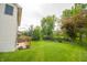 Beautiful backyard featuring a wooden deck, stone retaining wall, a well-manicured lawn, and mature trees at 6039 Chinkapin Dr, Columbus, IN 47201