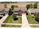 Aerial view of the red brick home, showcasing its manicured lawn and long driveway at 6212 N Woods Edge Dr, McCordsville, IN 46055