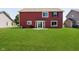 Spacious backyard and patio with a large manicured lawn and a red vinyl-sided house at 6212 N Woods Edge Dr, McCordsville, IN 46055