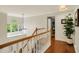Bright hallway with hardwood floors, wooden banister, and a large window showcasing outdoor scenery at 7248 River Birch Ln, Indianapolis, IN 46236