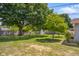 Spacious backyard featuring mature trees, a storage shed, and the home's exterior, offering a serene outdoor retreat at 8120 E 11Th St, Indianapolis, IN 46219