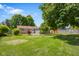 Expansive green backyard with mature trees, complemented by the home's exterior and well-kept lawn at 8120 E 11Th St, Indianapolis, IN 46219