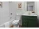 Stylish bathroom with a bathtub, white tile surround, decorative art, and green vanity at 8120 E 11Th St, Indianapolis, IN 46219
