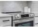 Close up of the stainless steel oven with glass cooktop and white countertops at 8120 E 11Th St, Indianapolis, IN 46219
