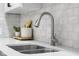 Close up of kitchen featuring stainless steel sink, modern faucet, white subway tile backsplash, and white countertop at 8120 E 11Th St, Indianapolis, IN 46219