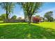 Lush green yard with mature trees and a privacy fence defines this property's ample outdoor space at 813 Stoner Dr, Anderson, IN 46013