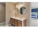 Bathroom featuring double sinks with wood cabinets, circular mirrors, and a glimpse into an adjacent bedroom at 8238 Crackling Ln, Indianapolis, IN 46259