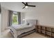 Bedroom featuring a queen bed, gray accents, a ceiling fan, and a view of a large tree through a window at 8238 Crackling Ln, Indianapolis, IN 46259