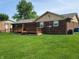 Backyard view of brick home with wood deck, lawn, and mature landscaping at 8510 E Mcgregor Rd, Indianapolis, IN 46259
