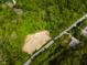 Aerial view of a wooded lot with cleared space for development along a road with traffic at 9602 Fall Creek Rd, Indianapolis, IN 46256