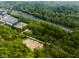 Aerial view of a wooded lot with a river in the background, road, and industrial park nearby at 9602 Fall Creek Rd, Indianapolis, IN 46256