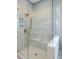 Bright and airy shower featuring beige marble tiling, a built-in bench, and glass enclosure at 9602 Fall Creek Rd, Indianapolis, IN 46256