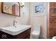 Bathroom featuring exposed brick, a sink with storage, and a toilet at 989 Woodruff Pl E Dr, Indianapolis, IN 46201