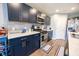 The kitchen is equipped with dark blue cabinets, stainless steel appliances, light stone backsplash, and wood floors at 1021 Boots Trl, Greenfield, IN 46140