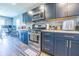 The kitchen has dark blue cabinets, stainless steel appliances, and a gray tile backsplash, and wood floors at 1021 Boots Trl, Greenfield, IN 46140