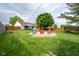 Lush backyard with fire pit, swing set, trampoline, and white house in the background at 1084 Lake W Dr, Brownsburg, IN 46112