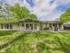 A large yard features a well-manicured lawn and a patio with white rocking chairs at 12 Windridge St, Country Club Heights, IN 46011