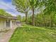 Lush backyard features a well-maintained lawn, mature trees, and a patio with outdoor seating at 12 Windridge St, Country Club Heights, IN 46011