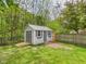 Storage shed in backyard with double doors, ramp and tidy landscaping, providing extra storage space at 12 Windridge St, Country Club Heights, IN 46011