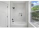 Bright bathroom features a built-in tub with shower and decorative tile, plus a large window at 1231 Marlowe Ave, Indianapolis, IN 46202