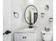 Powder room with a white vanity, marble countertop, oval mirror, and wall-mounted decorative planters at 14130 Autumn Woods Dr, Carmel, IN 46074