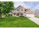 Charming brick and siding home with a manicured lawn, American flag, and inviting front porch at 14130 Autumn Woods Dr, Carmel, IN 46074