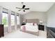 Main bedroom with a ceiling fan, tufted headboard, bedside lamps, and large windows with curtains at 14130 Autumn Woods Dr, Carmel, IN 46074