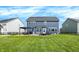 Expansive backyard view showcasing the blue house, fenced yard, patio with furniture, and lush green lawn at 15717 Hush Hickory, Westfield, IN 46074