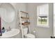 Cozy bathroom featuring a pedestal sink, toilet, decorative ladder shelf, and natural light from a window at 15717 Hush Hickory, Westfield, IN 46074
