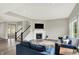 Spacious living room with a fireplace, a comfortable blue sofa, and an open staircase at 15717 Hush Hickory, Westfield, IN 46074